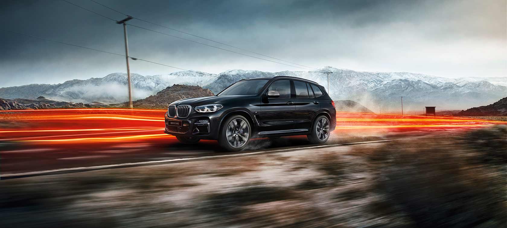 BMW X3 M40i и BMW X3 M40d, вид сбоку. BMW X3 M40i и BMW X3 M40d, черный металлик Black Sapphire, в движении, внешний вид, вид сбоку на фоне горного пейзажа, полосы света.